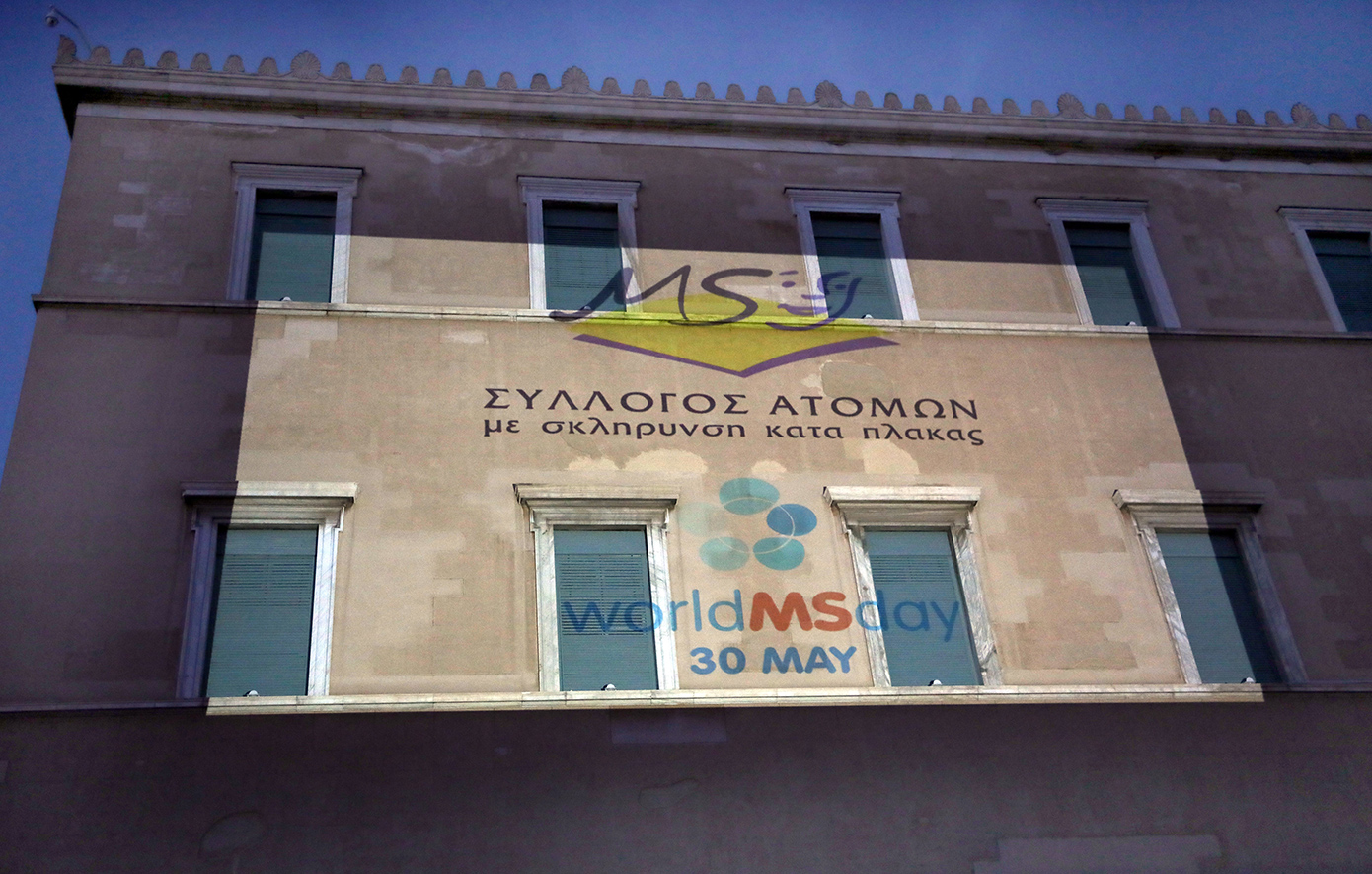 Βουλή: Λαμπερή φωταγώγηση της πρόσοψης με το έμβλημα του Συλλόγου Ατόμων με Σκλήρυνση Κατά Πλάκας