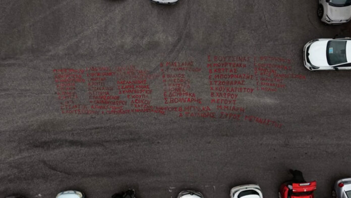 Δίκη για τα Τέμπη: Τα ονόματα των 57 θυμάτων ζωγραφισμένα με μπογιά μπροστά στο συγκρότημα «Γαιόπολις»